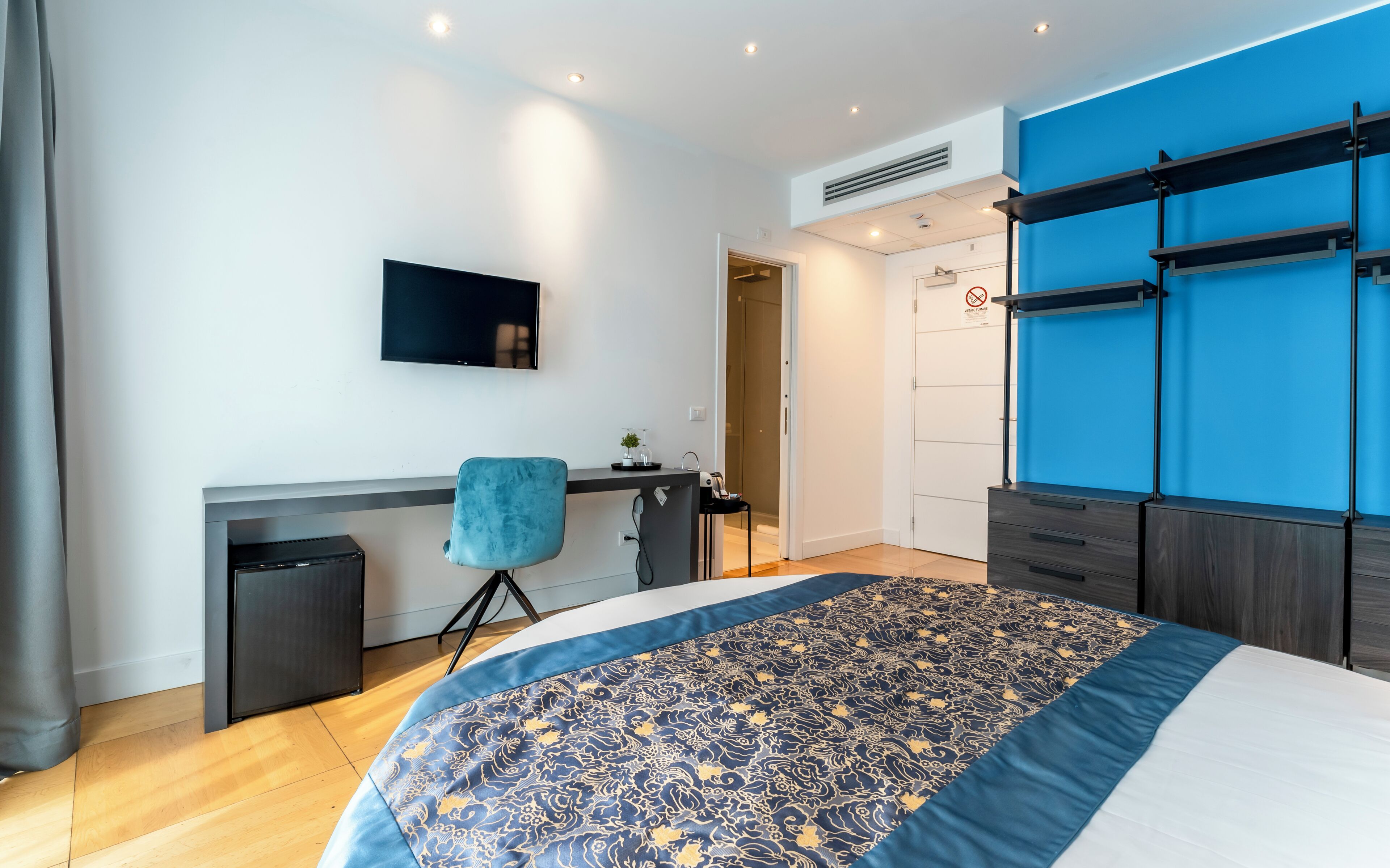 A modern hotel room with a bed, a desk, and a TV.
