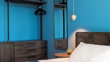 A bedroom with a bed, a dresser, a round table with a plant, and a hanging light fixture.