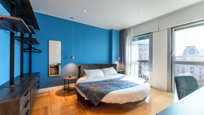 A modern bedroom with a large bed, a desk, and a view of the city through a large window. - La Dimora di Missori (Milan)