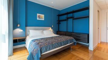 A bedroom with a bed, bedside table, and a wall-mounted shelf unit.