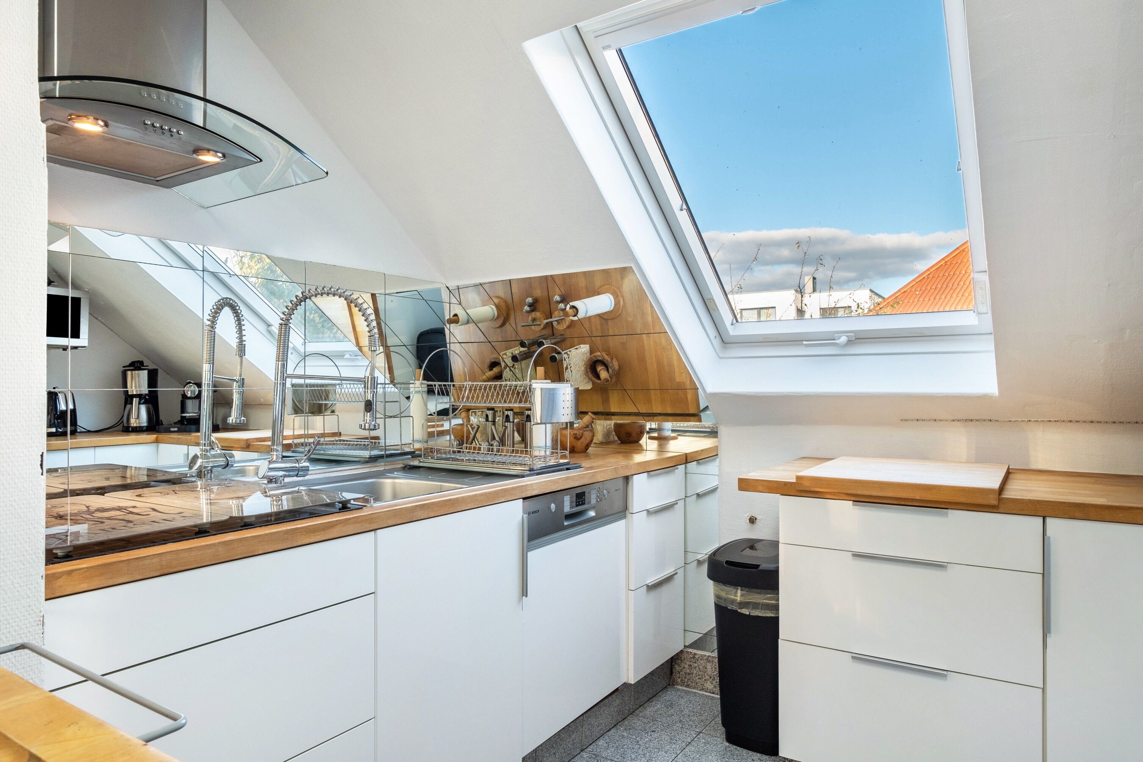 A modern kitchen with a skylight, stainless steel appliances, and a wooden countertop.