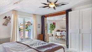 A bedroom with a large bed, a ceiling fan, a view of the outside, and a dining area. - Apartment 'Fewo-wosink' with private terrace, balcony and Wi-Fi (Bad Krozingen)