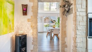 A stone archway leading to a dining area with a table and chairs, a wall-mounted decorative piece, and a large abstract painting. - Apartment 'Fewo-wosink' with private terrace, balcony and Wi-Fi (Bad Krozingen)