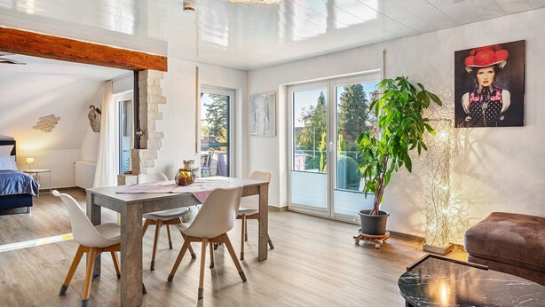 A modern interior with a dining area, a large potted plant, and a painting on the wall. - Apartment 'Fewo-wosink' with private terrace, balcony and Wi-Fi (Bad Krozingen)