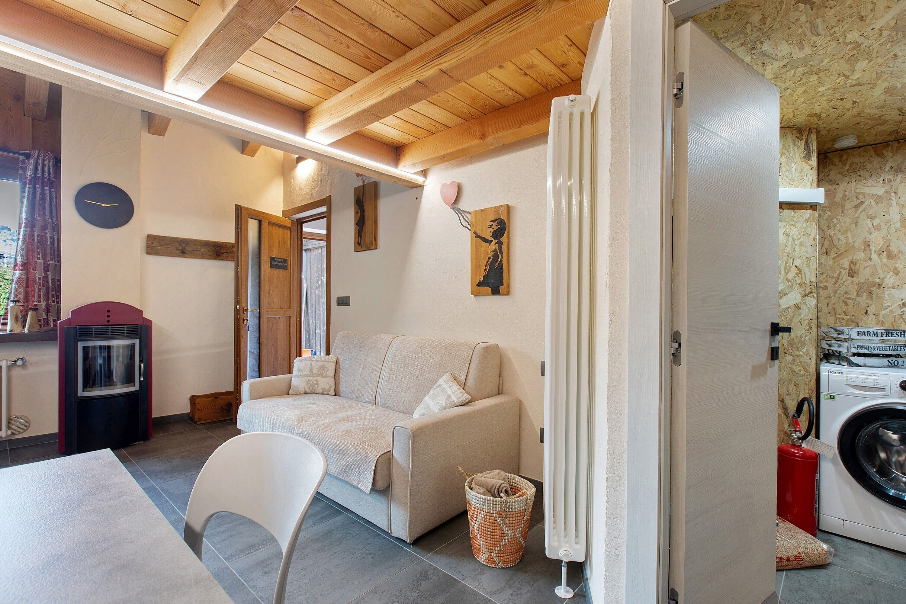 Une pièce confortable avec un canapé, un fauteuil, une horloge, un radiateur et un lave-linge.
