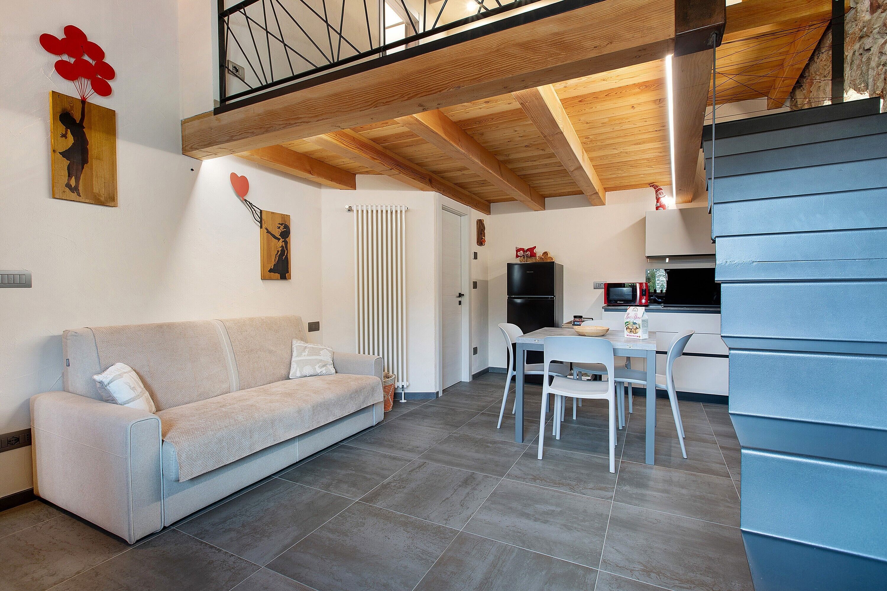 Een woonkamer met een bank, een eettafel met stoelen, een keuken met inbouwapparatuur en een trap.