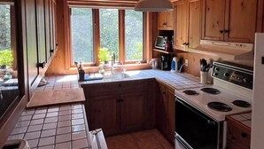 Une cuisine avec des meubles de rangement en bois, une cuisinière et un évier.