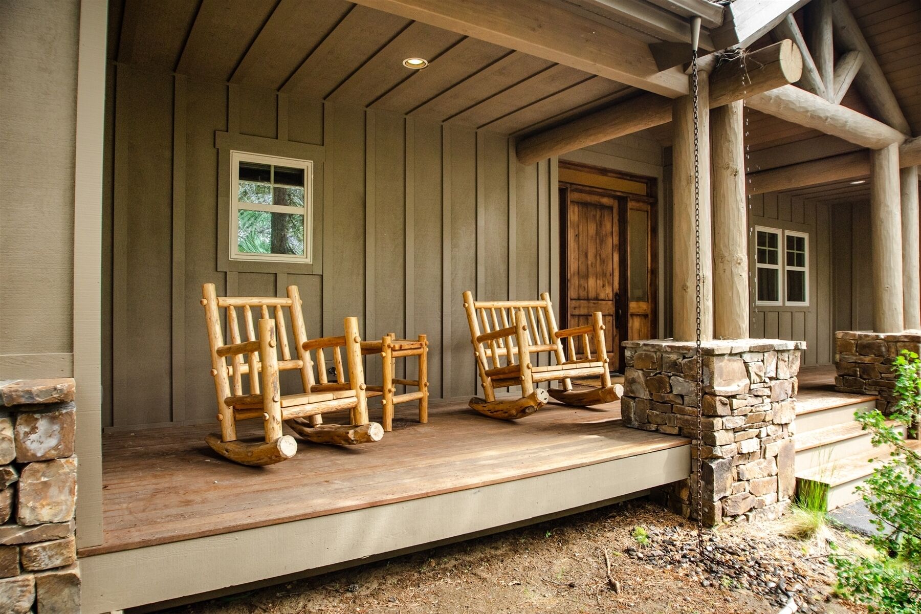 A wooden porch with two rocking chairs and a stone fireplace.