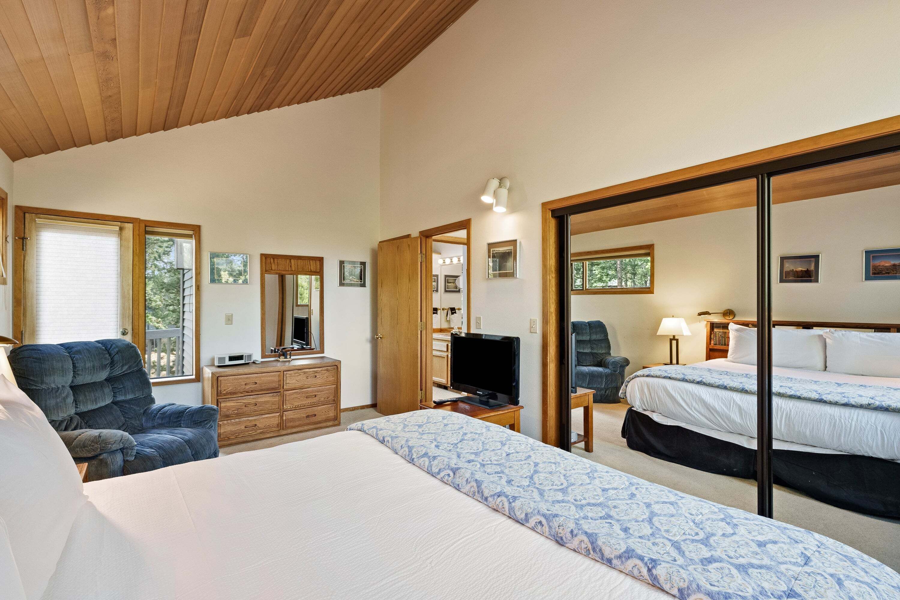A bedroom with a bed, a dresser, a television, and a chair.