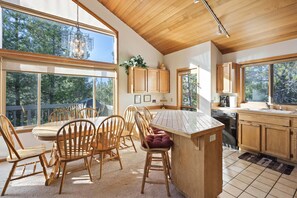A spacious kitchen with wooden cabinets, a large island, and a dining area with wooden chairs. - White Elm 29 - Classic Sunriver, A/C, Hot Tub, Large Deck (Sunriver)