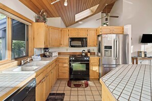 A modern kitchen with wooden cabinets, a stainless steel refrigerator, a built-in oven, and a microwave.