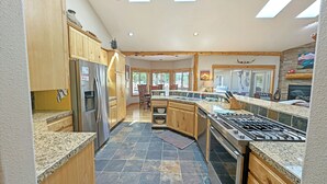 Une cuisine spacieuse dotée de plans de travail en granit, d’armoires en bois, d’un réfrigérateur en acier inoxydable et d’une cuisinière à gaz.
