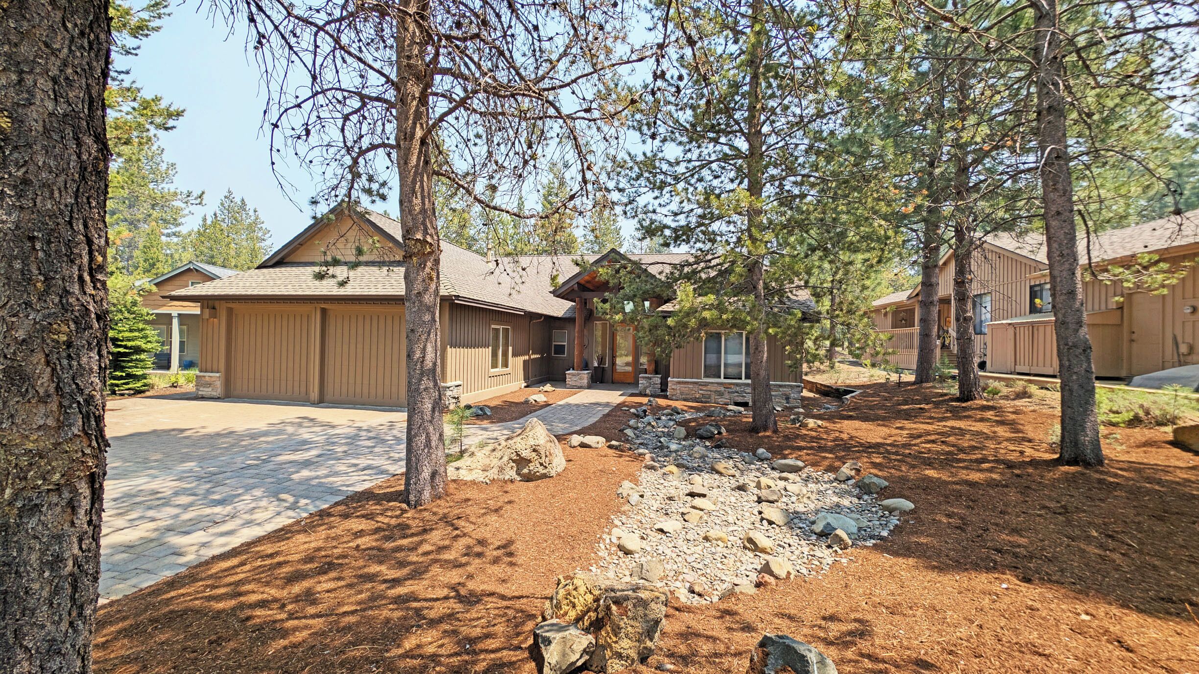A residential area with multiple houses, a stone pathway, and a well-maintained lawn.
