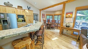 A kitchen with granite countertops, wooden cabinets, a refrigerator, and a dining area with a table and chairs.