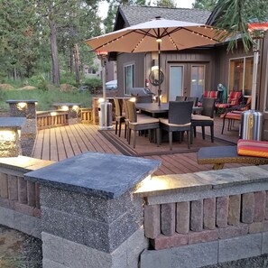 Una terraza con mobiliario exterior, una parrilla y luces colgantes.