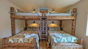 A bunk bed room with a ladder, two beds with patterned bedding, and two wall-mounted lamps. - Verdin 6 - Lovely Lodge Style home, A/C, Private Hot Tub (Sunriver)
