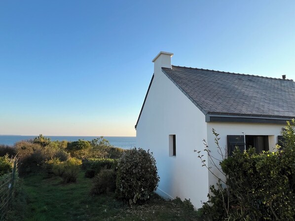 A white house with a tiled roof, a small window, and a view of the sea. - Maison de pêcheur vue mer, magnifique en toutes saisons ! (Clohars-Carnoët)