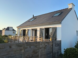 A single-story house with a sloped roof, a wooden fence, and a clear sky. - Maison de pêcheur vue mer, magnifique en toutes saisons ! (Clohars-Carnoët)