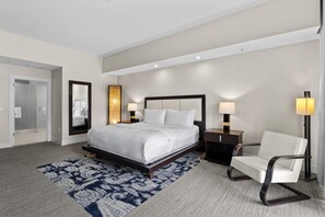 Une chambre d’hôtel moderne avec un grand lit, des tables de chevet, une chaise et un tapis à motifs.