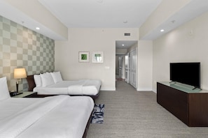 Une chambre d’hôtel avec deux lits, une télévision, un bureau et un sol recouvert de moquette.