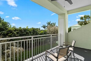 Un balcon avec une balustrade blanche, une table et des chaises.