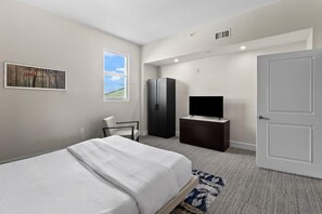 Une chambre d’hôtel avec un lit, un téléviseur posé sur une commode, une armoire et une porte.
