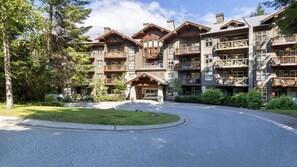 A multi-story lodge with balconies, a central entrance, and a landscaped driveway.
