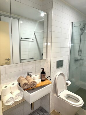 Un baño moderno con lavabo blanco, espejo y cabina de ducha de vidrio.