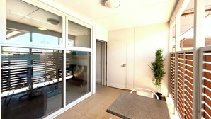 A small, bright room with a tiled floor, a table with chairs, a potted plant, and a sliding glass door leading to another room. - The Padbury Suites-Premium City Apartment (Bulgarra)