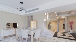 A modern dining area with a marble floor, white furniture, and a staircase leading to another level. - ALSAWAH Spacious Family Villa in Palm Hills Sheikh Zayed (6th of October City)