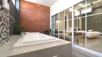 Un baño moderno con una bañera grande, una pared de acento de ladrillo y un ventanal con vistas a un dormitorio.