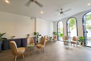 A spacious indoor area with multiple seating arrangements, including chairs and tables, and large windows allowing natural light. - Nanlamoon Hotel (Nan)