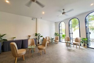 Un espacio interior amplio con diversas opciones de mobiliario, incluyendo sillas y mesas, y grandes ventanales que permiten la entrada de luz natural.