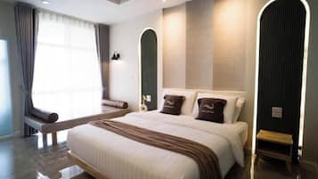 Una habitación de hotel moderna con una cama grande, un banco y una pequeña mesa.