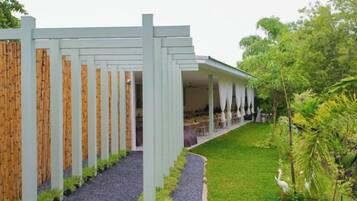A building with a covered outdoor area, a gravel pathway, and a green lawn.