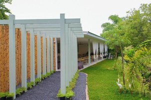 A building with a covered outdoor area, a gravel pathway, and a green lawn.