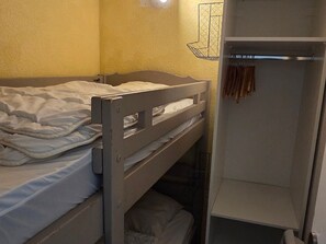 A bunk bed with a white blanket and a shelf with hanging items. - Charming Studio 4 Pers Ski-In/Out Avoriaz (Avoriaz)