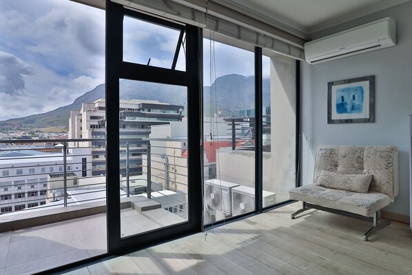 A modern room with large windows, a sofa, and an air conditioning unit.