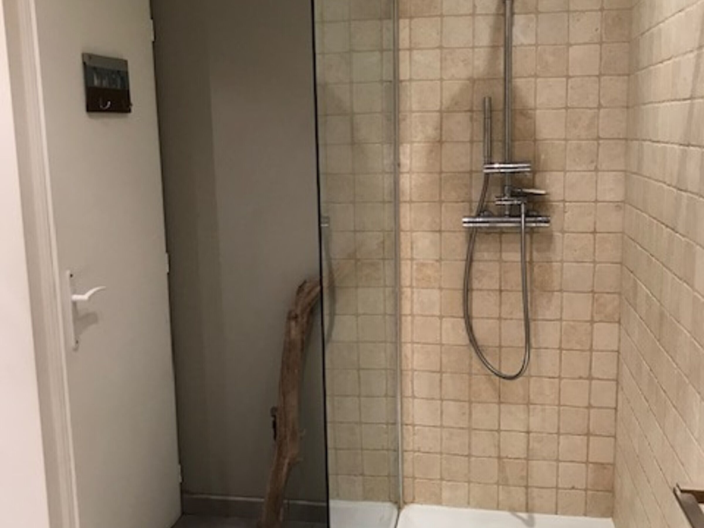 A bathroom with a glass shower enclosure, tiled walls, and a visible showerhead.