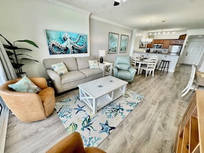 Una sala de estar con sofá, sillón, mesa de centro y alfombra con motivos de estrellas de mar.