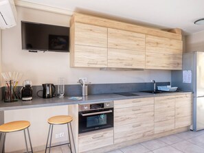 Una cocina moderna con armarios de madera, horno empotrado, refrigerador y televisor de pantalla plana.