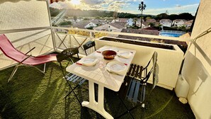 Een balkon met een tafel gedekt voor twee personen, met uitzicht op een woonwijk en een zwembad.
