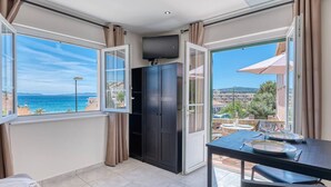 A room with a view of the sea, a dining table with chairs, a wardrobe, and a large window. - Air-Conditioned Apartment in Le Lavandou Center, Near Beach (Le Lavandou)