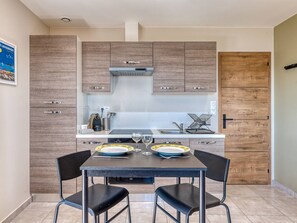 A modern kitchen with wooden cabinets, a stainless steel range hood, and a dining table with chairs.
