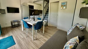 A compact living space with a dining area, kitchenette, and a staircase.