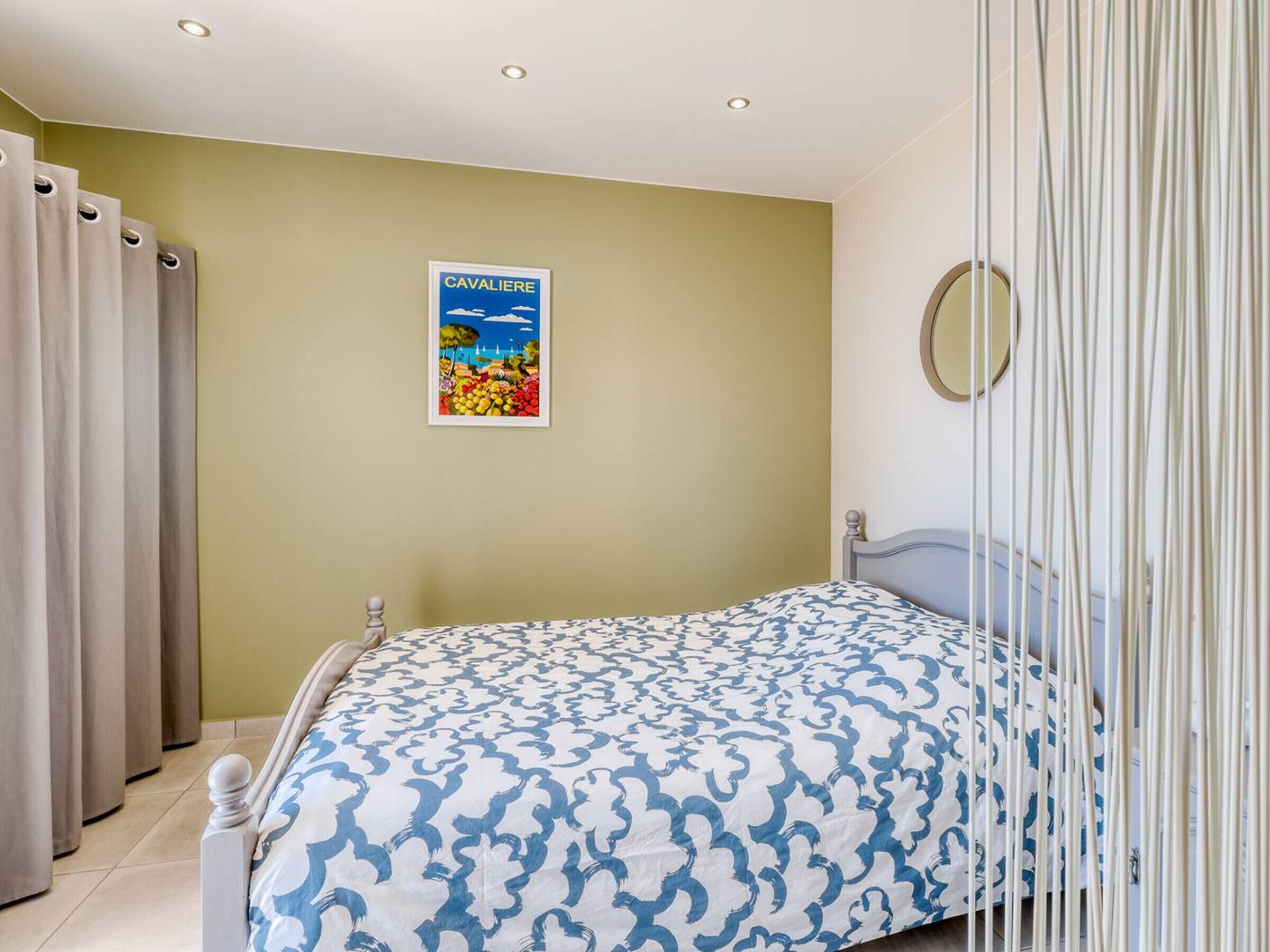 A bedroom with a bed, a poster on the wall, and curtains.