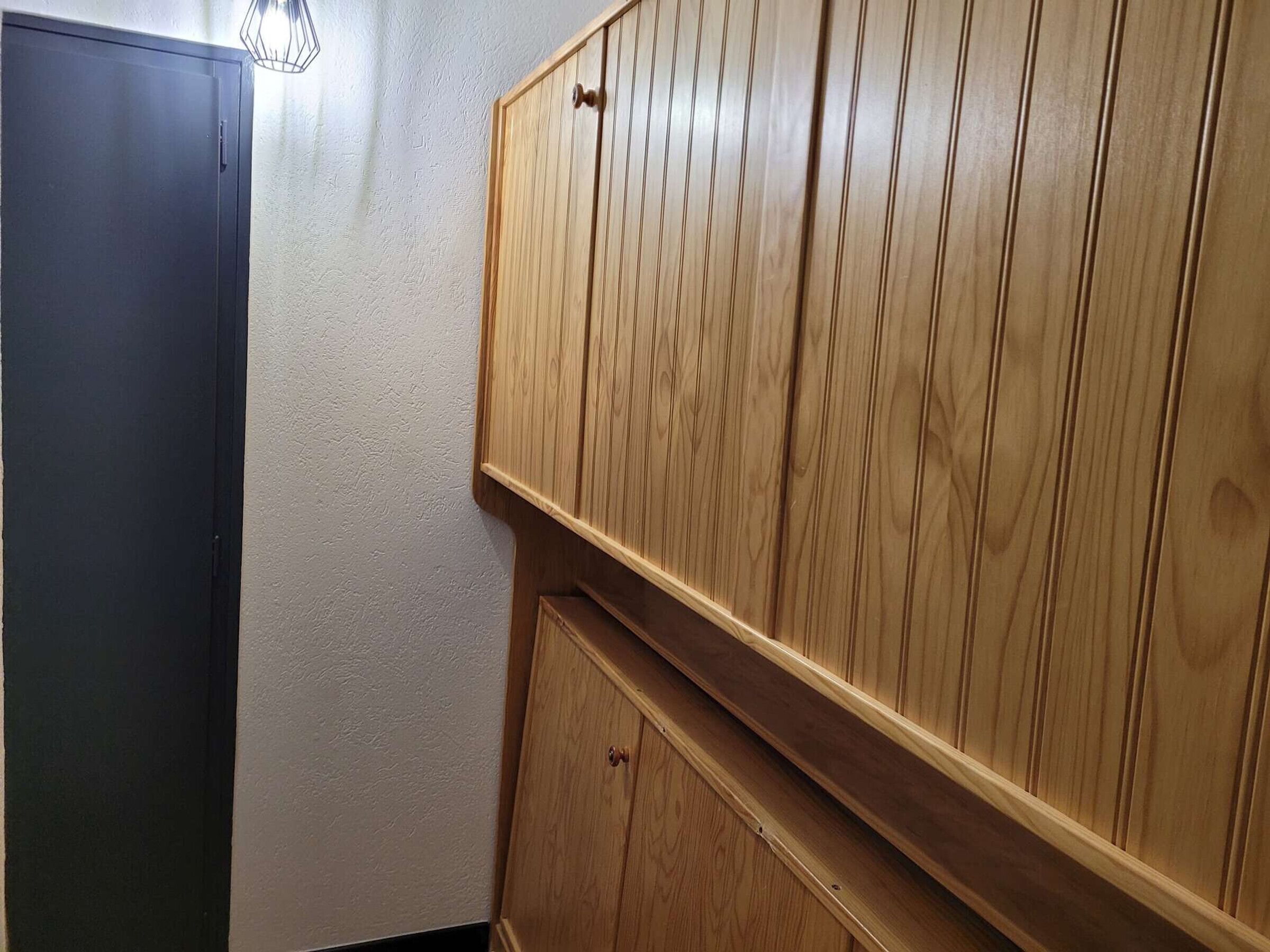 A corner of a room with a dark-colored cabinet and a wooden wardrobe with vertical slats.