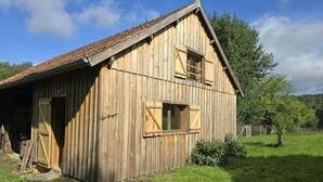 A wooden barn with a sloped roof, a door, and a window.