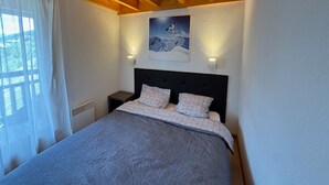 Een slaapkamer met een bed, twee nachtkastjes, een schilderij en een raam met gordijnen.