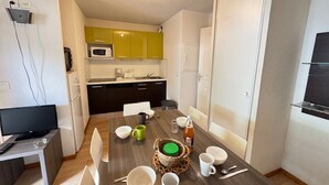 Een ruimtelijke woonruimte met een eethoek, kitchenette en een televisie.